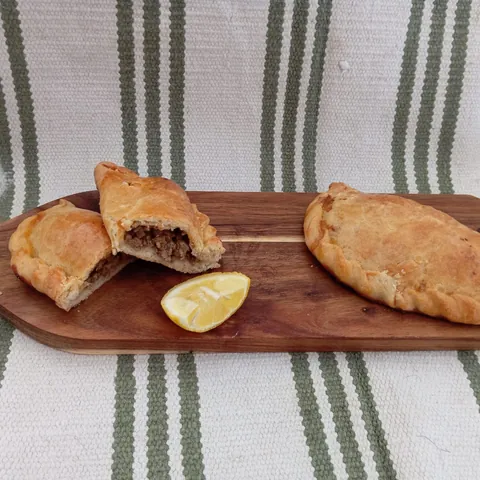 Empanadilla de carne abierta sobre tabla de madera