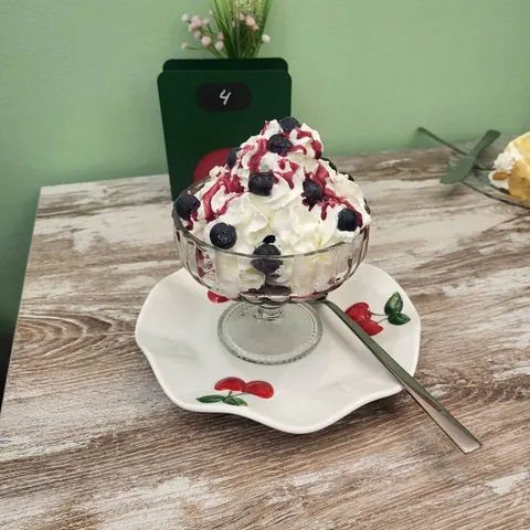Trifle en copa de cristal con nata, arándanos y salsa de frutos rojos